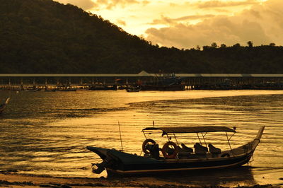 Boats moored in river against sky during sunset