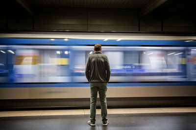 Rear view of man standing on train at railroad station