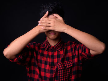 Midsection of person wearing hat standing against black background