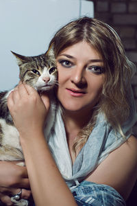 Portrait of a woman in a cape hugging a cat in the studio