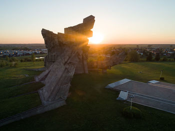 Built structure on field against sky during sunset