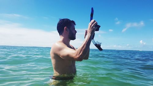 Full length of shirtless man in sea against sky