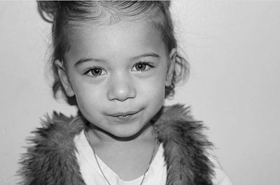 Close-up portrait of girl standing against wall