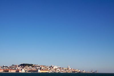 Town by sea against clear blue sky