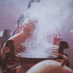 Close-up of boy praying at temple amidst smoke