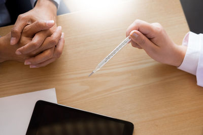 Doctor holding thermometer at table