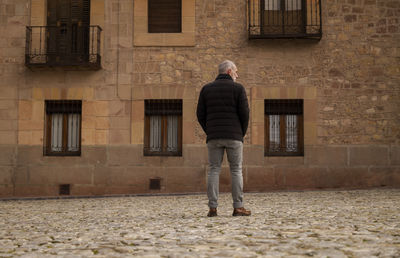 Adult man in winter clothes standing against old building. siguenza, castilla la mancha, spain