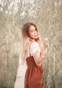 Portrait of young woman standing against plants