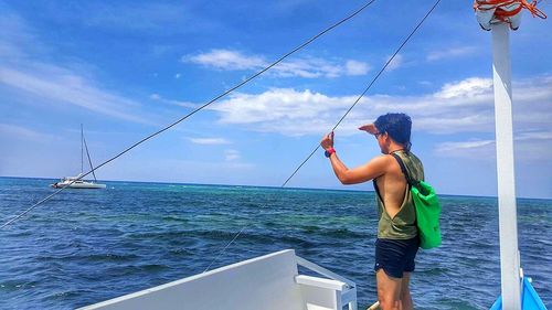 Man fishing in sea against sky