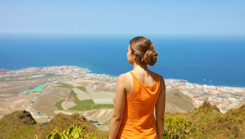 Rear view of woman looking at sea shore against sky