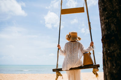 Rear view of woman with umbrella standing on beach