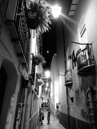 Low angle view of people walking on illuminated street amidst buildings