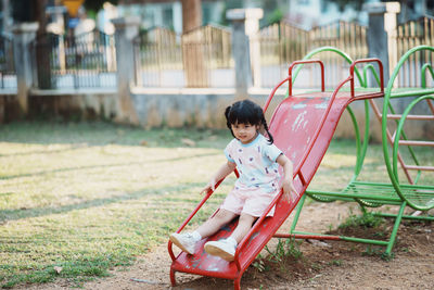 Side view of cute girl sitting in park