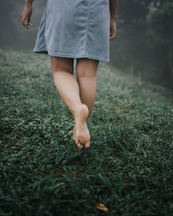 Low section of woman walking on field