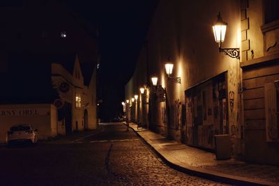 Illuminated street amidst buildings at night