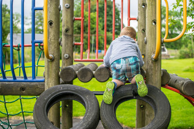 Rear view of boy playing on structure at park