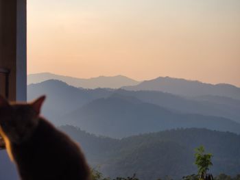 Person on mountain against sky during sunset