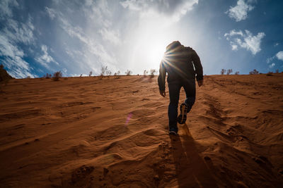 Rear view of man walking on sand dune