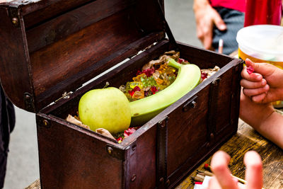 High angle view of fruits with colorful candies in box on table