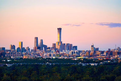 Modern buildings in city against sky during sunset