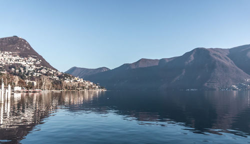 Scenic view of lake and mountains against clear blue sky