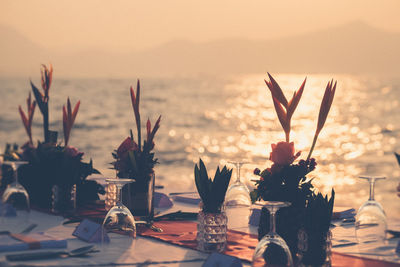 Close-up of vase on table against sea during sunset