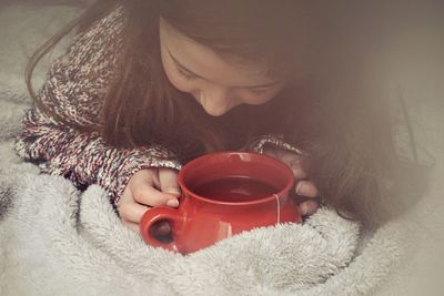 High angle view of girl holding tea cup on blanket