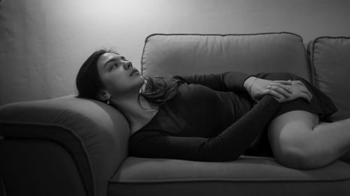 Young woman sitting on sofa at home