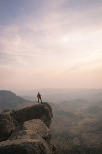 Man standing on rock against sky