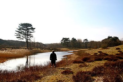 Rear view of woman standing on lakeshore