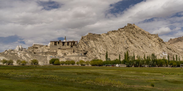 Built structure on landscape against cloudy sky