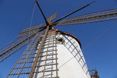 Low angle view of traditional windmill against blue sky