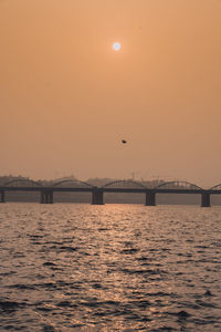 Bridge over sea against sky during sunset