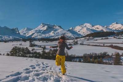 A full-body shot of a young caucasian woman running towards the camera in the french alps mountains