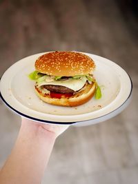 Cropped hand holding burger in plate