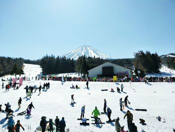 People on snow covered landscape against sky