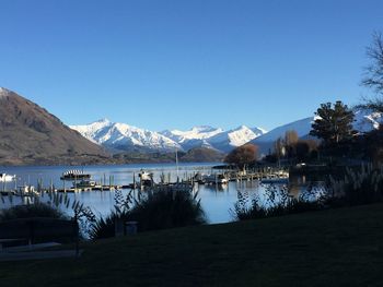 Scenic view of lake and mountains against clear blue sky