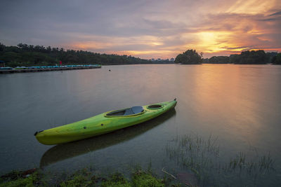 Kayak moored at lake against sky during sunset