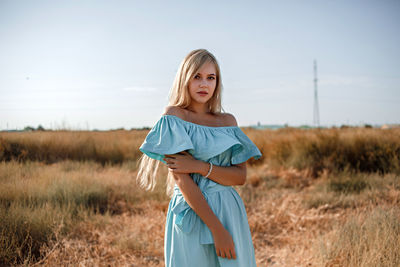 Portrait of teenage girl wearing dress standing on land against sky