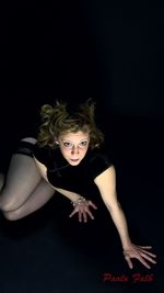 Portrait of young woman against black background