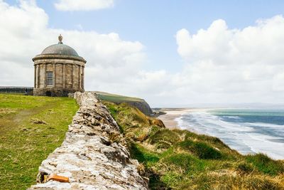 Mussenden temple on cliff by sea against sky