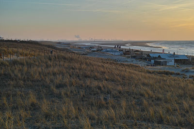 Sunset over the dunes of the north sea coast, beach clubs, people walking, port of rotterdam