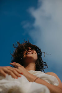 From below of cheerful young woman with wet hair relaxing on sandy beach on sunny day
