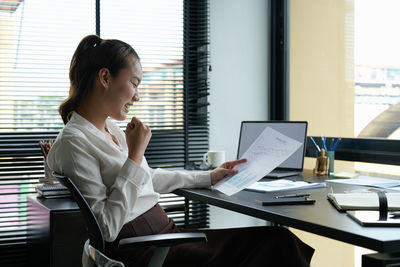 Businesswoman using laptop while sitting on table