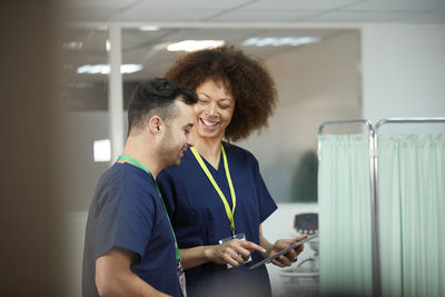 Smiling nurse with tablet pc looking at colleague in medical room