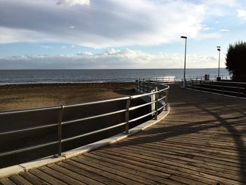 Empty pier over sea against sky