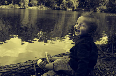 Cute boy sitting by lake