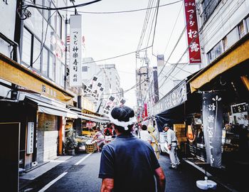 Rear view of man standing on street against buildings in city