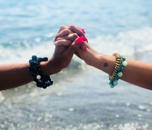 Close-up of woman hand over sea against blurred background