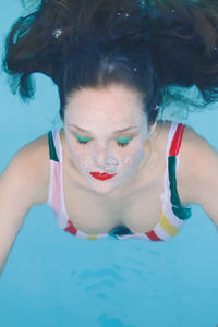 Close-up of a brunette girl with hair submerged in the pool with her eyes closed